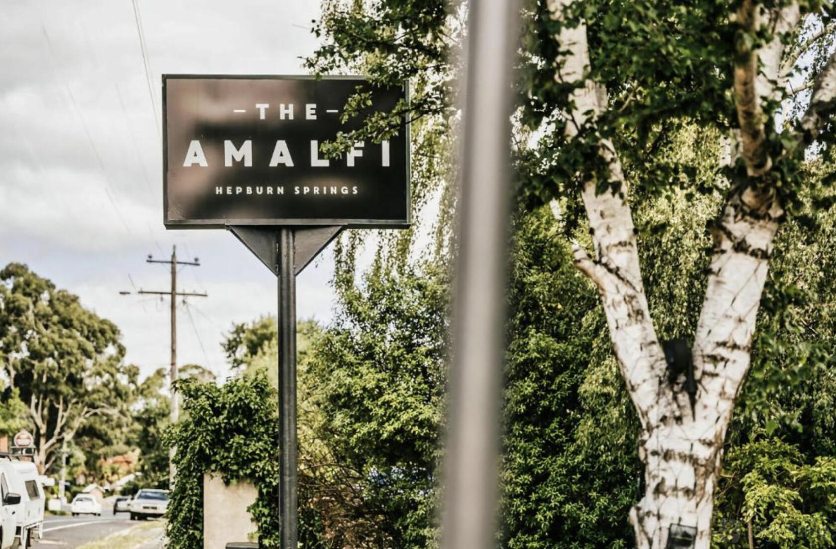 A hotel entrance sign surrounded by trees and greenery at The Amalfi.
