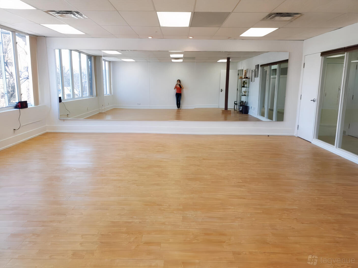 A dance studio with floor-to-ceiling mirrors, wooden flooring, and large windows at Dance ConneXion Studio - Sheppard.