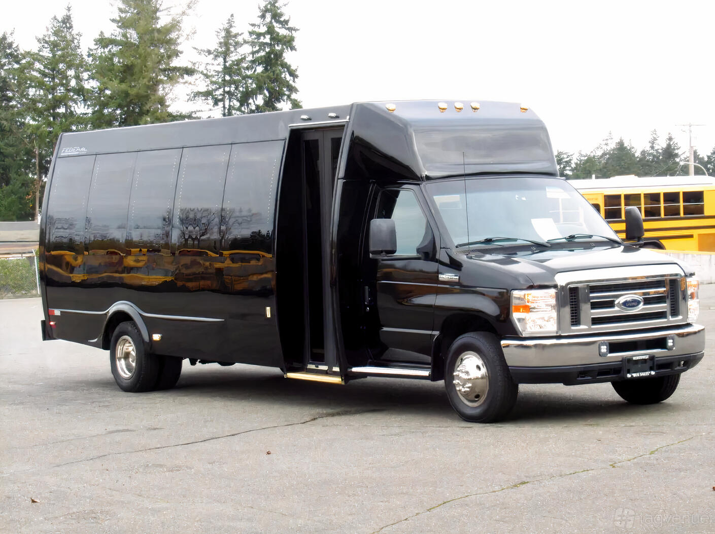 A black party bus with tinted windows and an open entry door parked outside at Famous Drive.