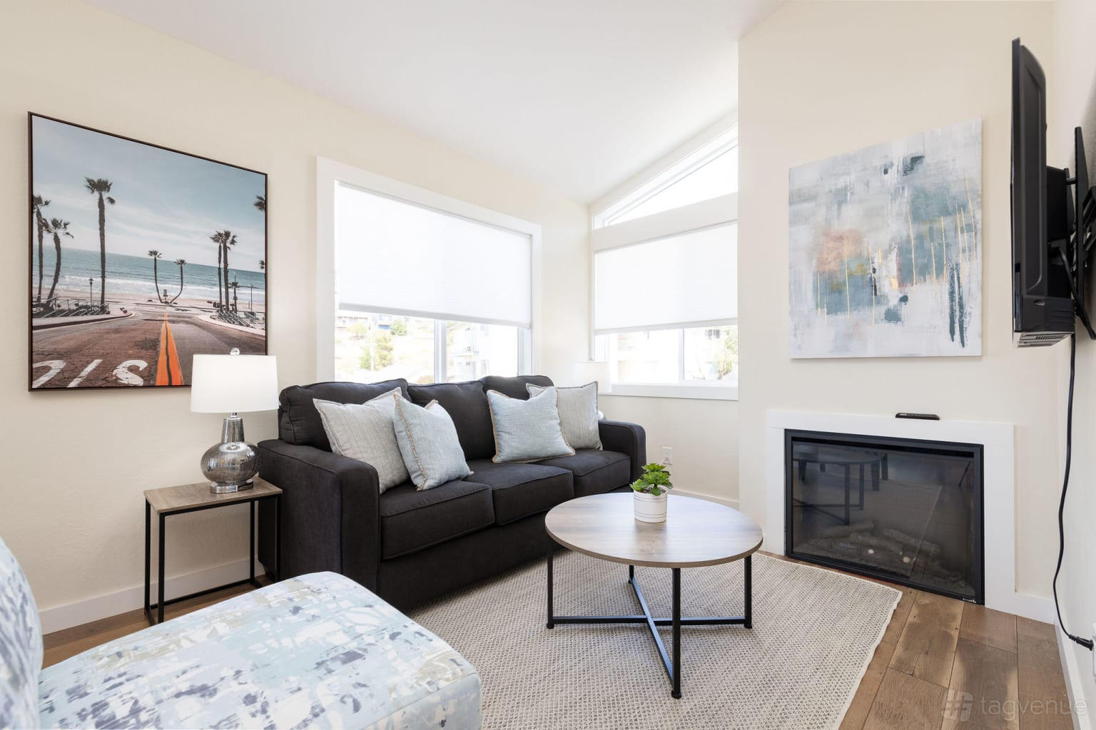 An apartment living room with a dark sofa, round coffee table, fireplace, and large windows at Private Townhome.
