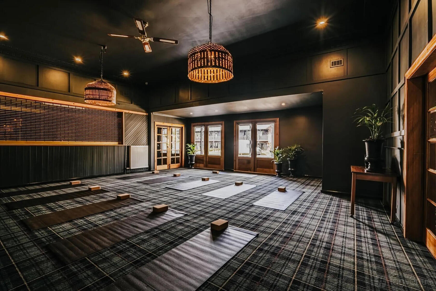 A hotel room with plaid carpet, yoga mats, woven pendant lights, and large windows at The Amalfi.