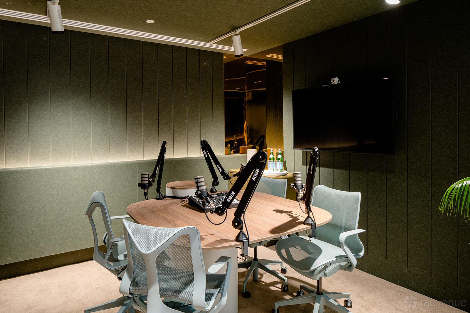 A meeting centre with a podcast studio, round table, microphones on adjustable arms, and office chairs at Centred.