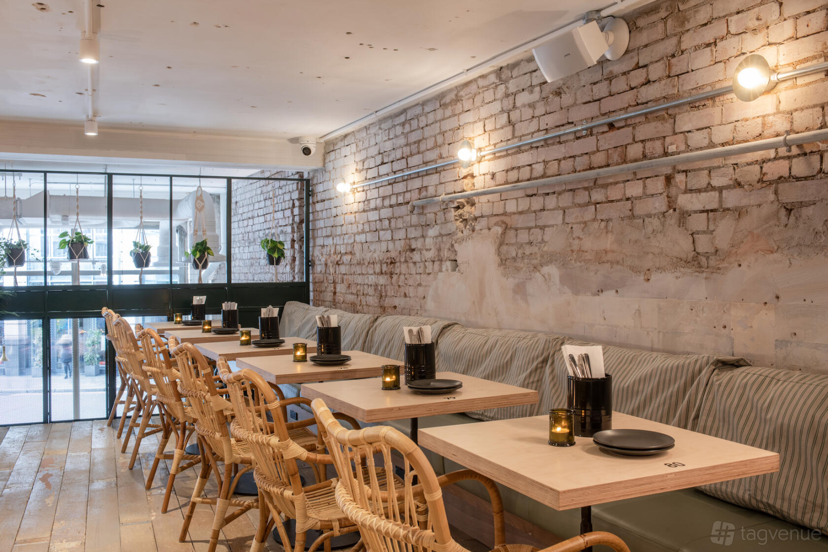 An event space with exposed brick walls, large windows, and rattan chairs at Vagabond Monument.