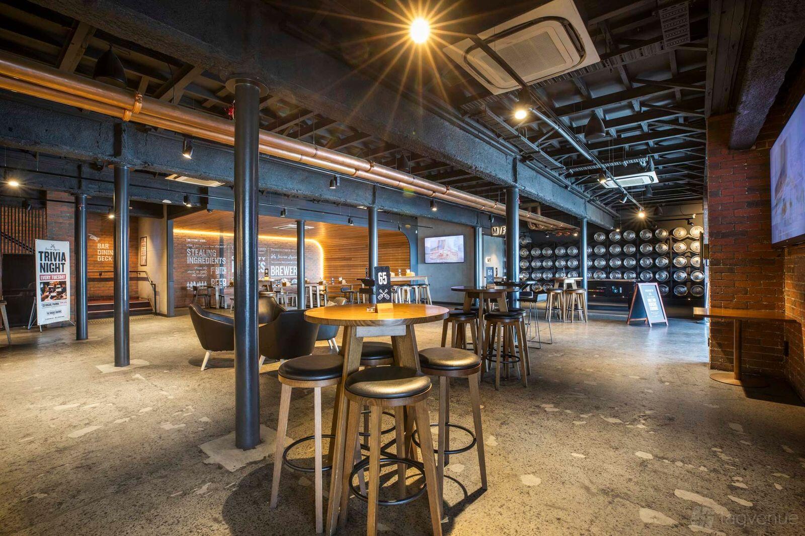 A bar in a pub with high tables, barrel-lined walls, and exposed ceilings at The Rogue Squire.