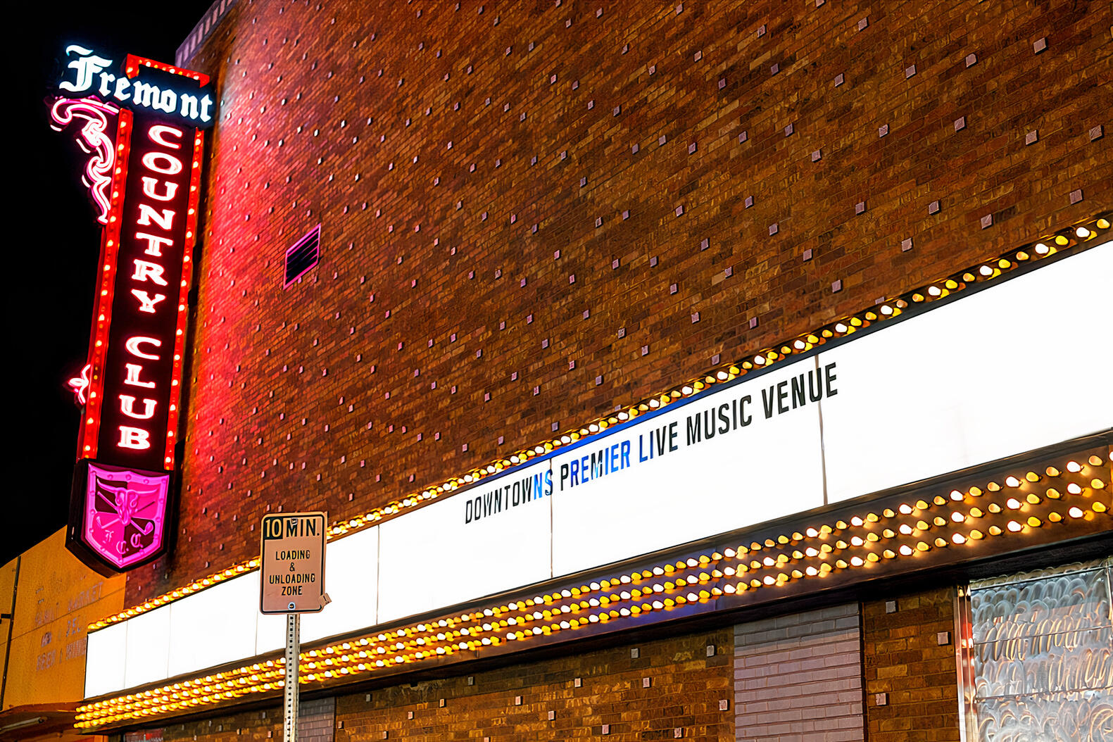 An event space with a vintage brick exterior and a neon Fremont Country Club sign above a marquee.