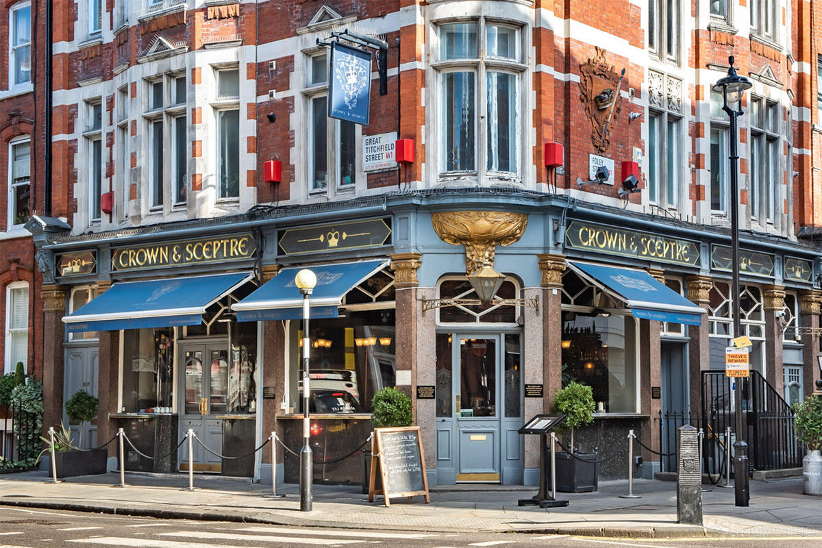 A traditional pub with blue awnings, outdoor signage, and decorative gold details at The Crown and Sceptre.