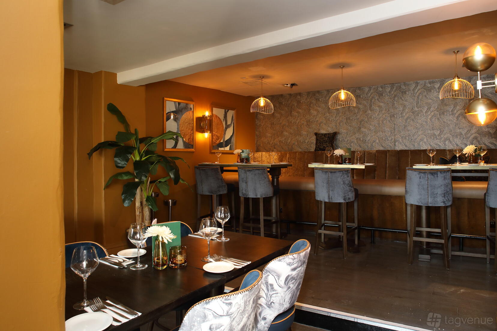 A pub with patterned accent walls, velvet chairs, and hanging pendant lights at The Encore.