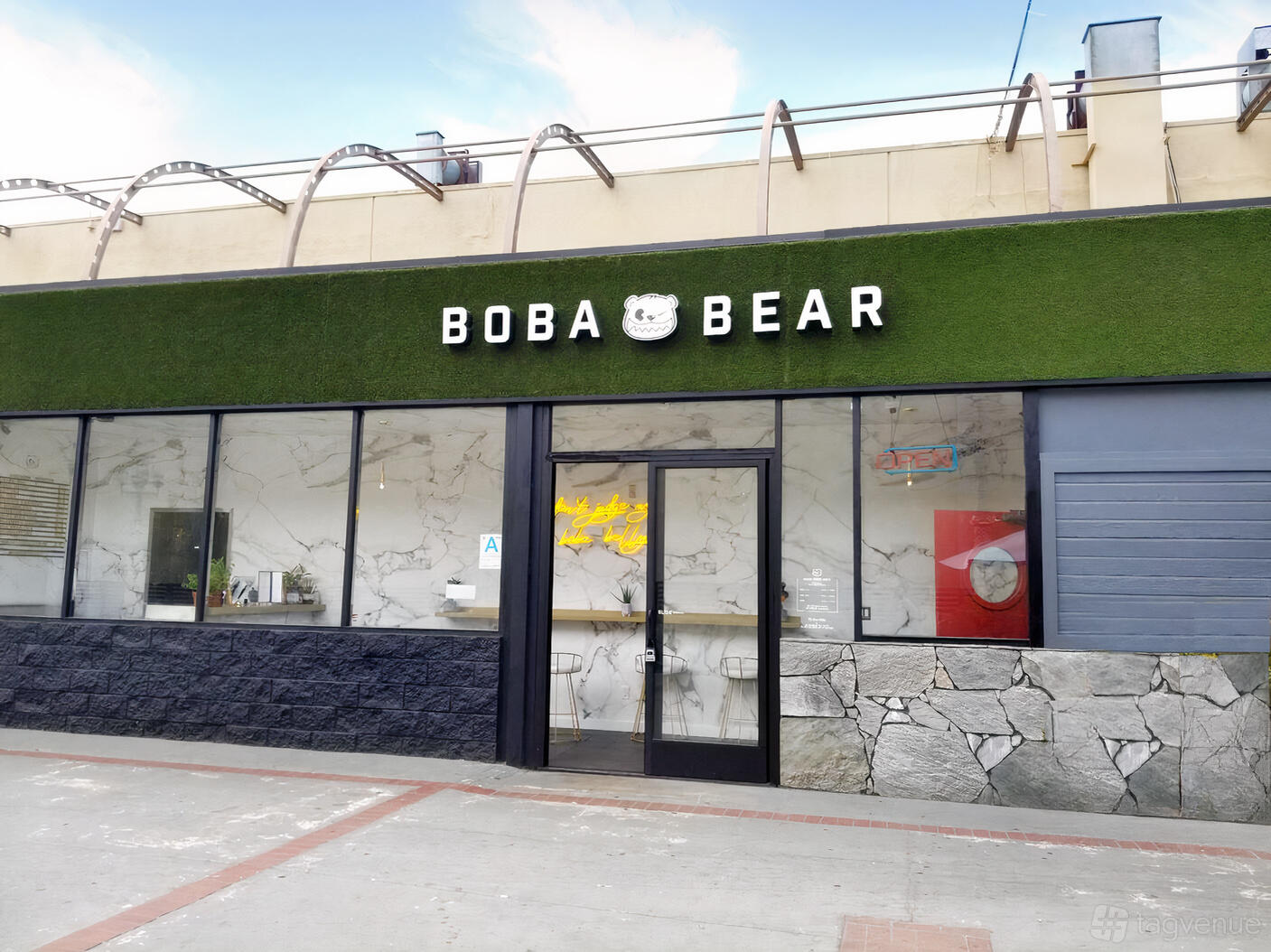 A café with a marble facade, black trim, and artificial green turf signage at Boba Bear Rowland Heights.
