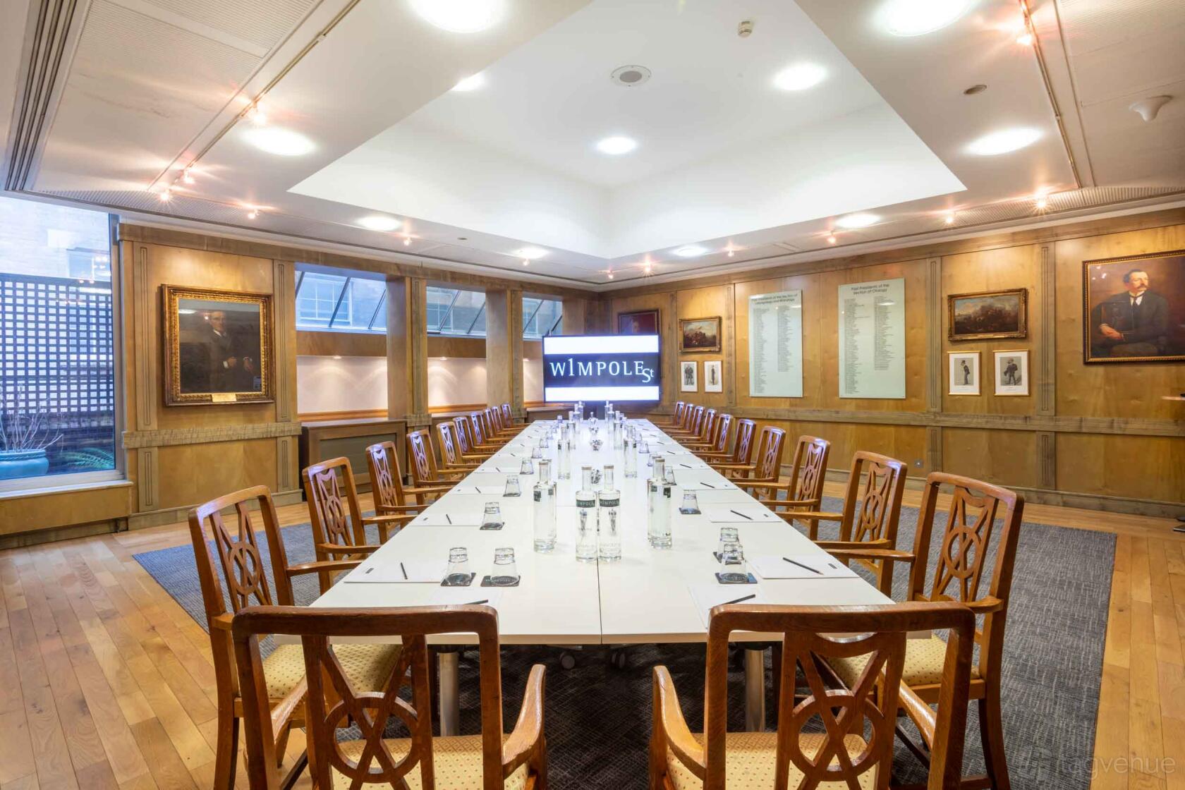 An event venue with a long conference table, wooden chairs, and wall-mounted portraits at 1 Wimpole Street.