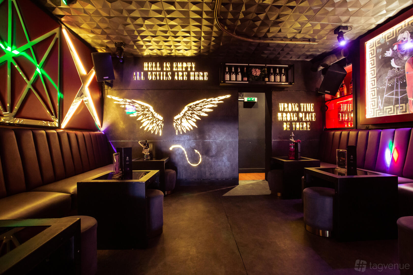 An event space with leather banquette seating, neon wing art, and vibrant wall lighting at Soul Lounge.