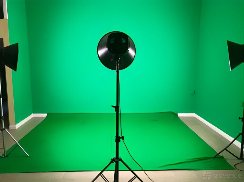 A photo studio with a seamless green screen backdrop and three professional lighting stands at Humza Studio.