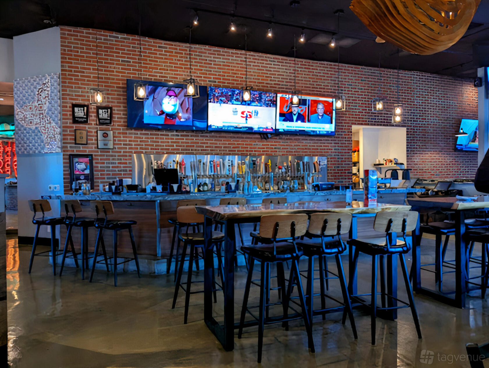 A restaurant with a long bar, exposed brick walls, multiple flat-screen TVs, and high wooden stools at SLATER’S 50/50 LAKE MEAD.