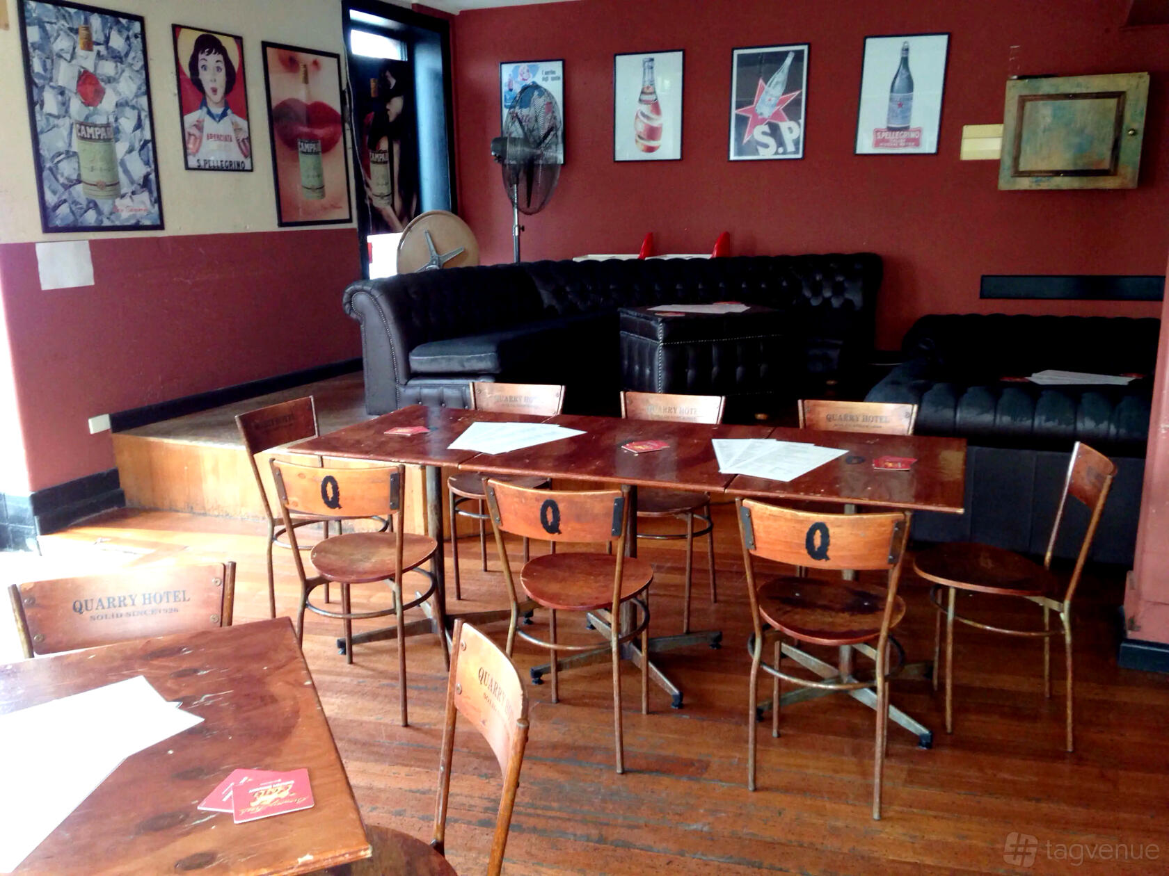 A bar in a pub with wooden tables and chairs, vintage posters, and leather sofas at The Quarry Hotel.
