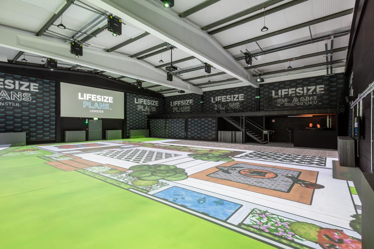 A warehouse with exposed beams and a large printed floor plan display at Lifesize Plans Ireland.