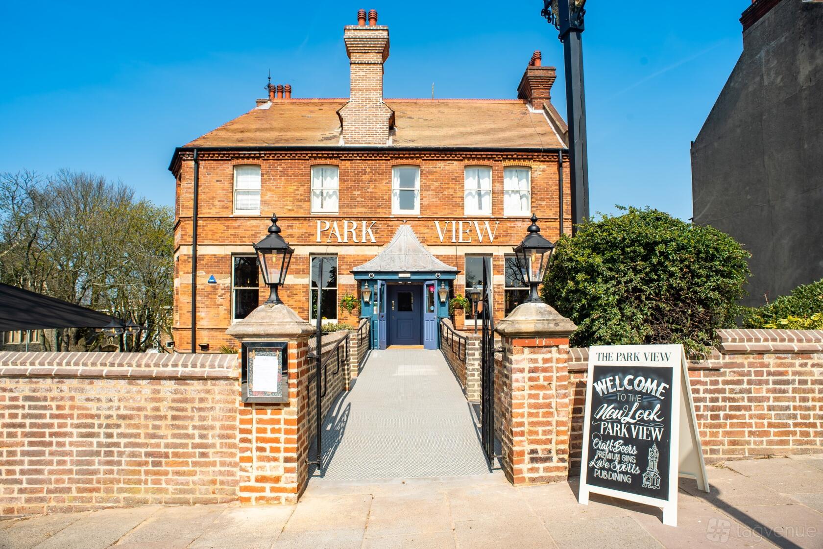 A traditional brick pub with large front windows, double chimney stacks, and a welcoming entrance at The Park View.