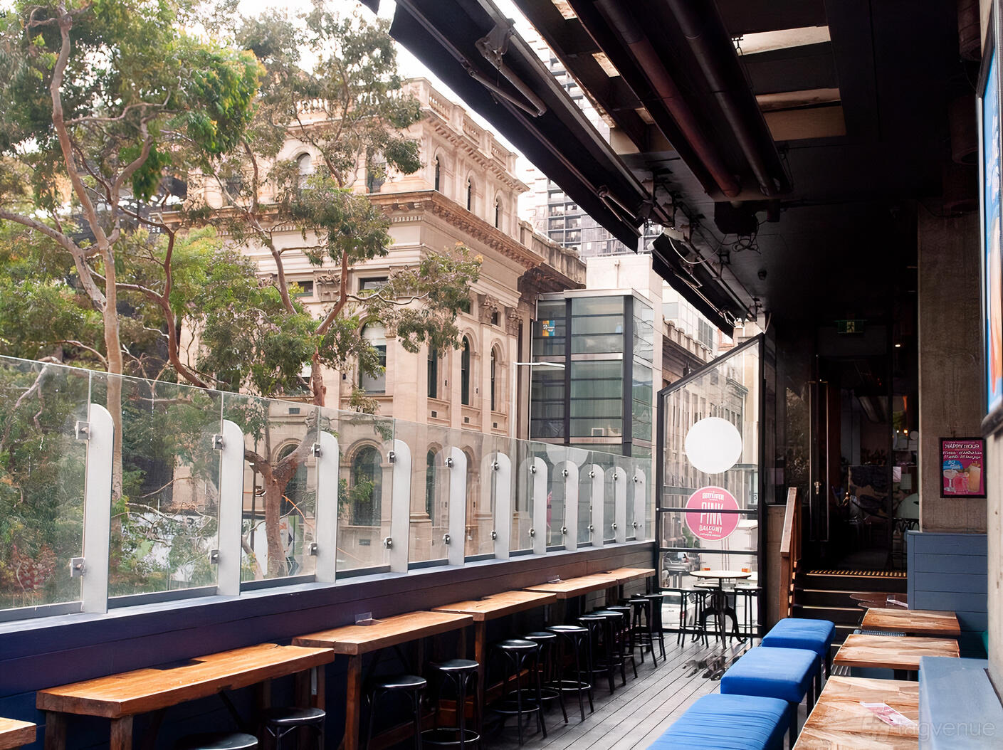 An outdoor restaurant space with glass railing, wood tables, and city views at Father's Office.
