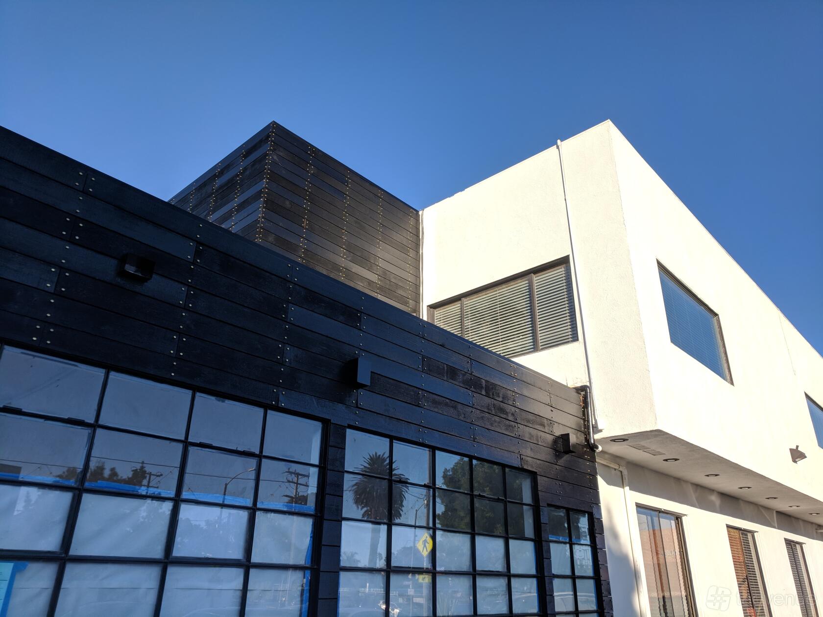 A coworking space with dark wood paneling and large industrial-style windows at Beach House CoWork.