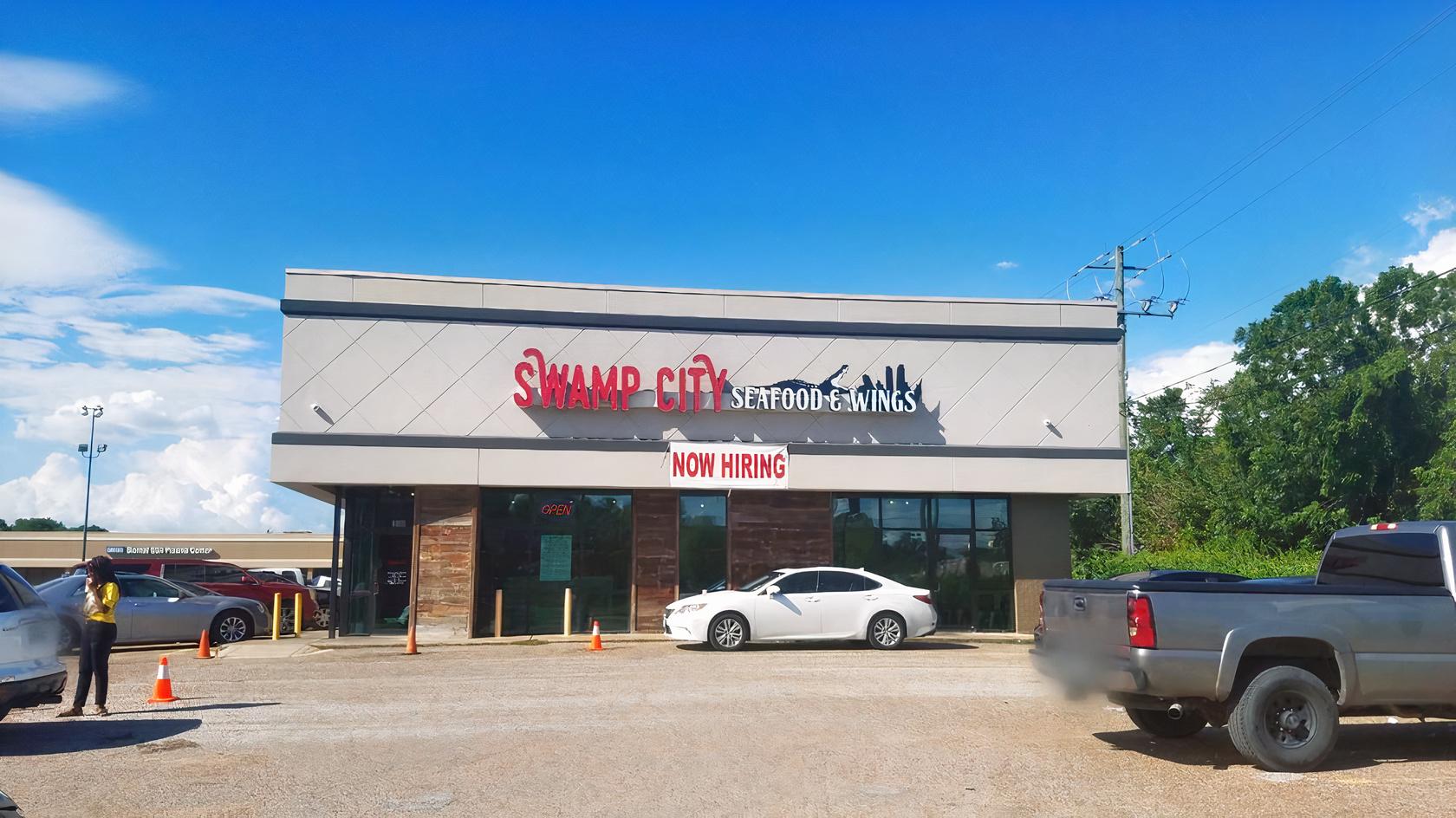 A restaurant with a flat-roof exterior, large front windows, and parking lot at Swamp City.