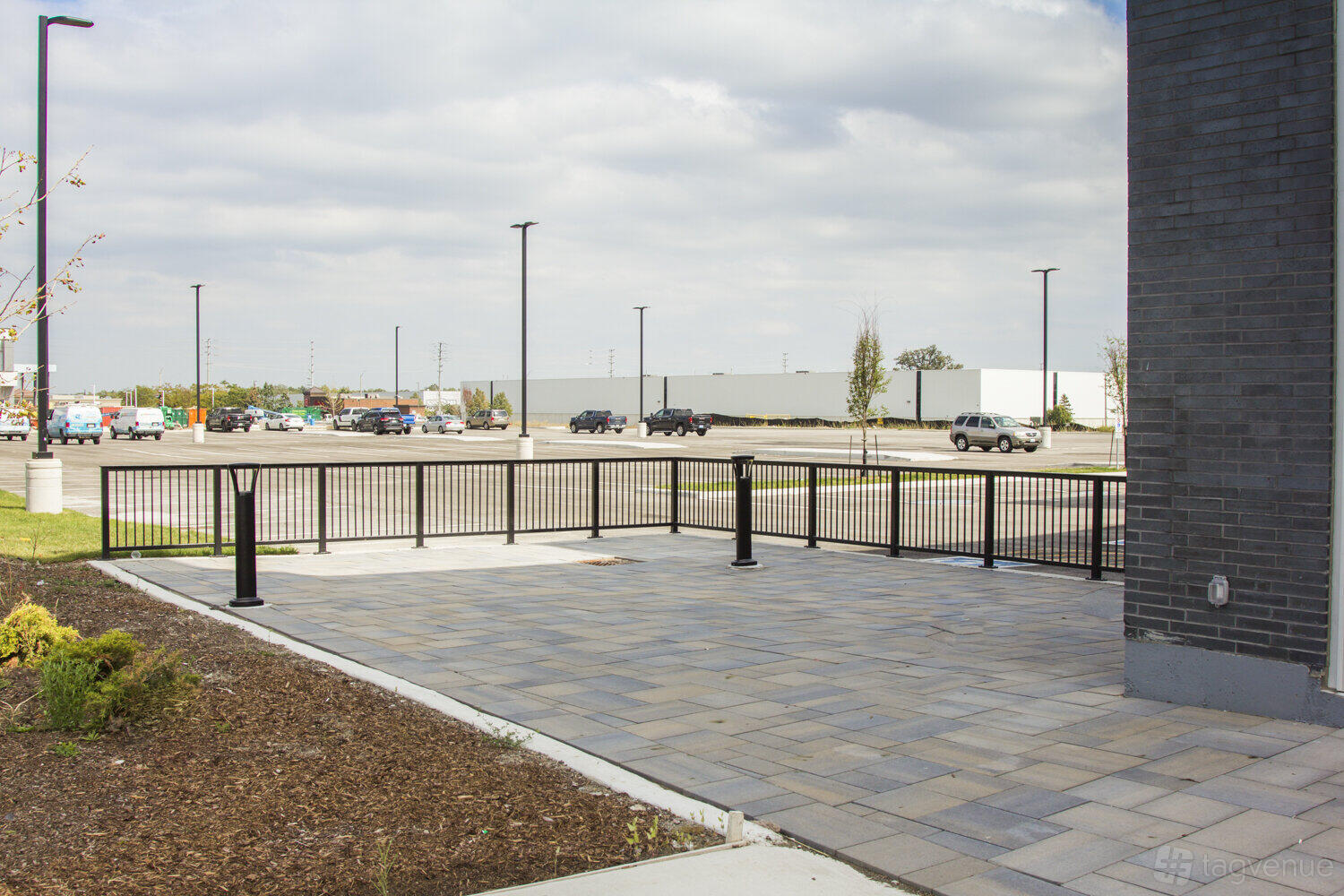 An outdoor patio with paved stone flooring and black metal fencing at Queen's Manor Event Centre.