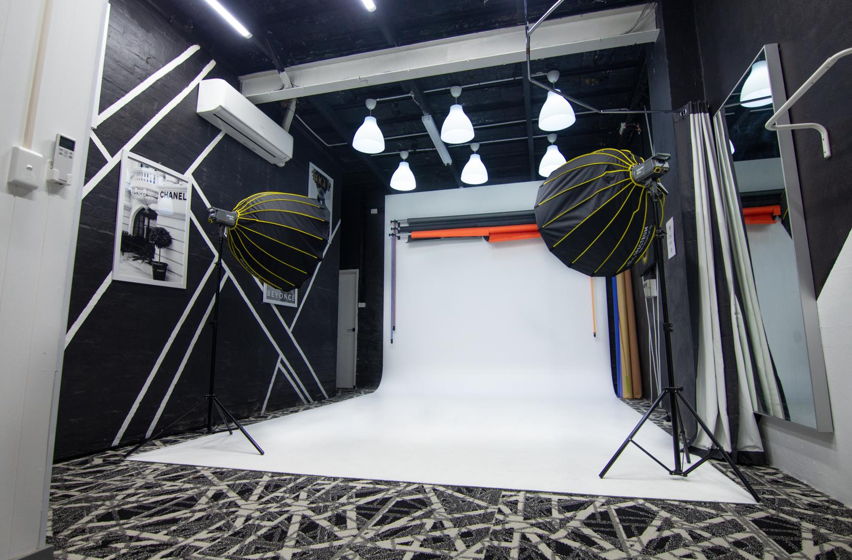 A photo studio with a white cyclorama wall, overhead lighting, and professional softbox lights at Metronome Studios.