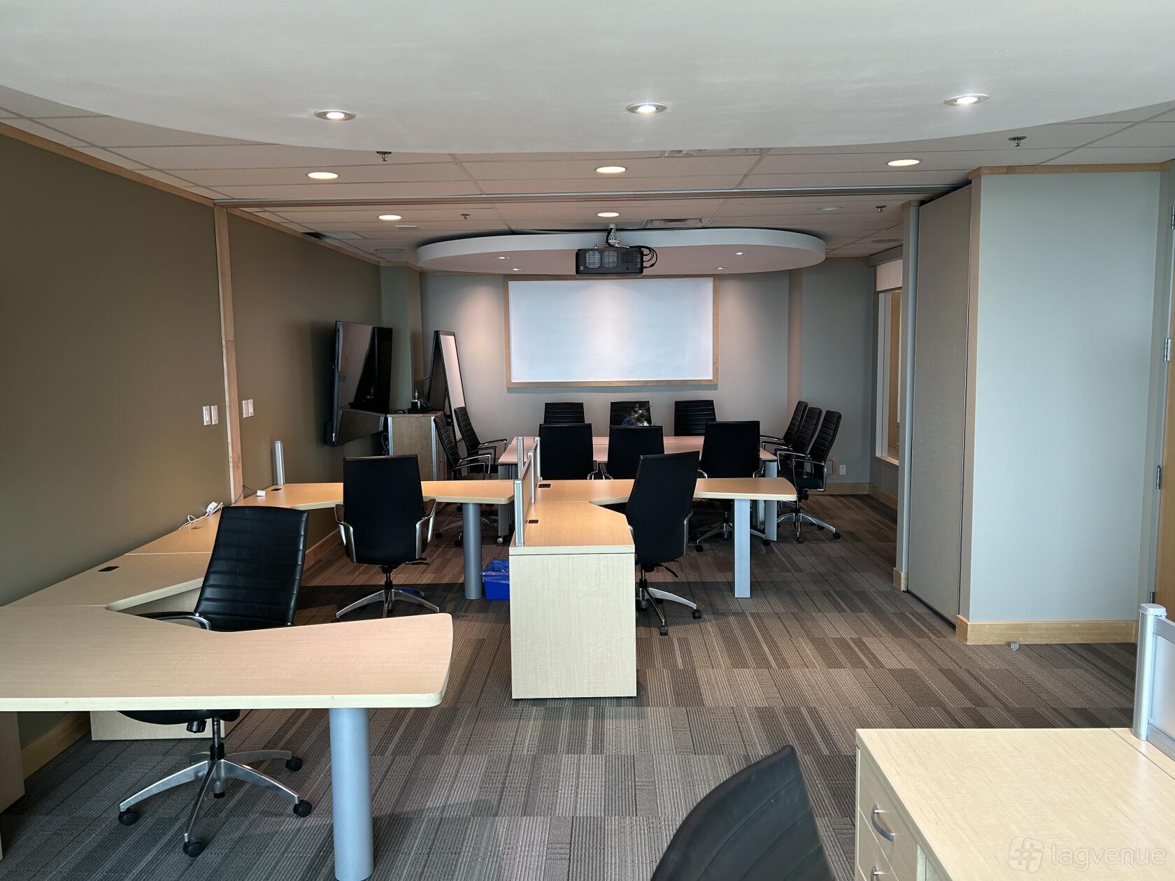 An office space with multiple desks, ergonomic chairs, a projector screen, and large windows at Intelligent Office (Hudsons Bay Centre).