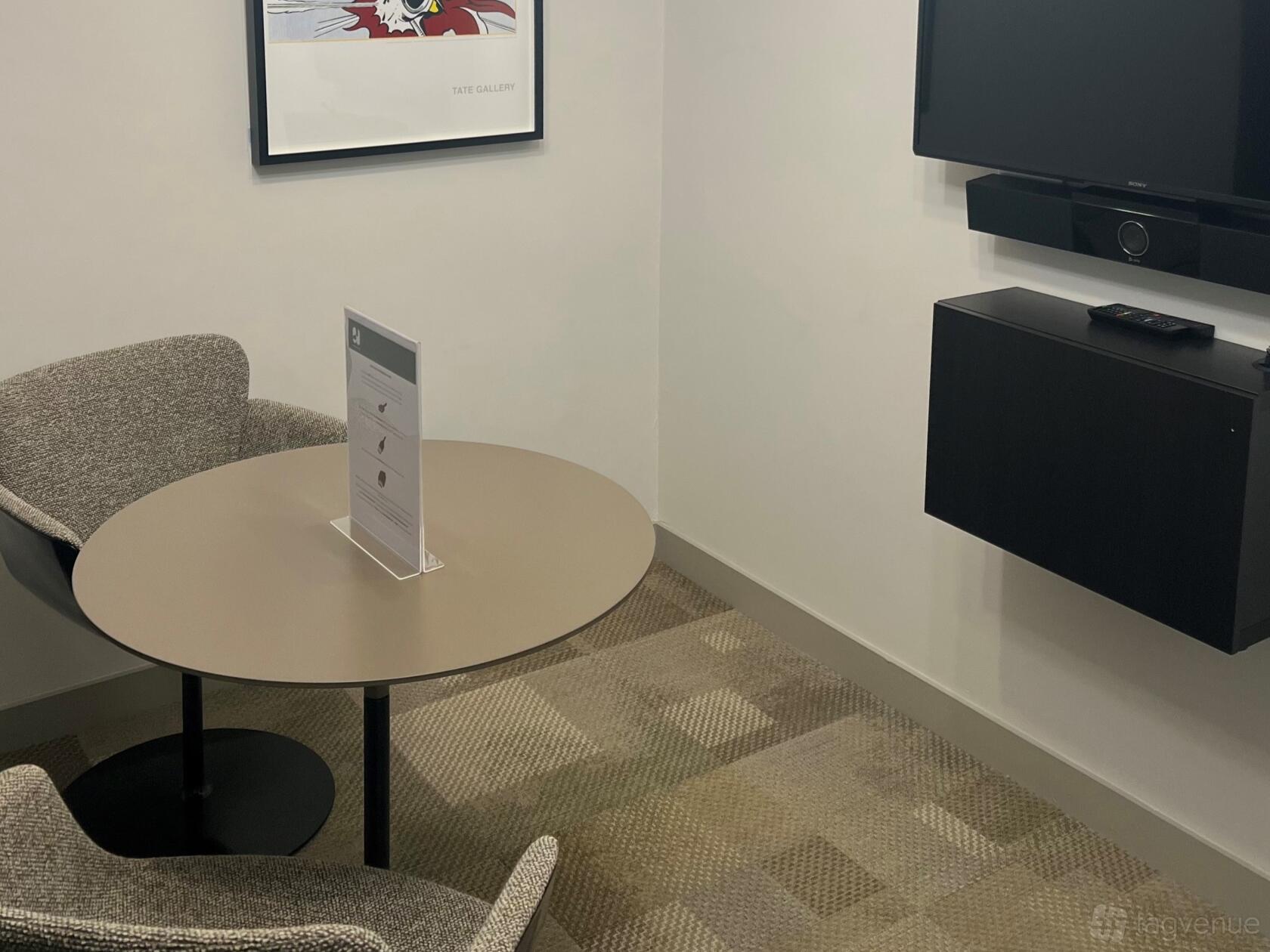 A meeting room with a round table, upholstered chairs, and wall-mounted screen at Phoenix House.