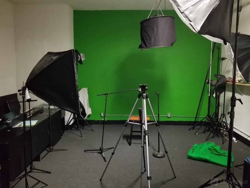A photo studio with a green screen, studio lighting, and video equipment at Artist Housing DTLA.