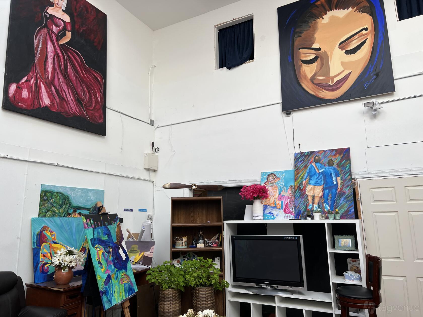 An event space with large colorful paintings, white walls, and shelves with plants and decor at Bazart.