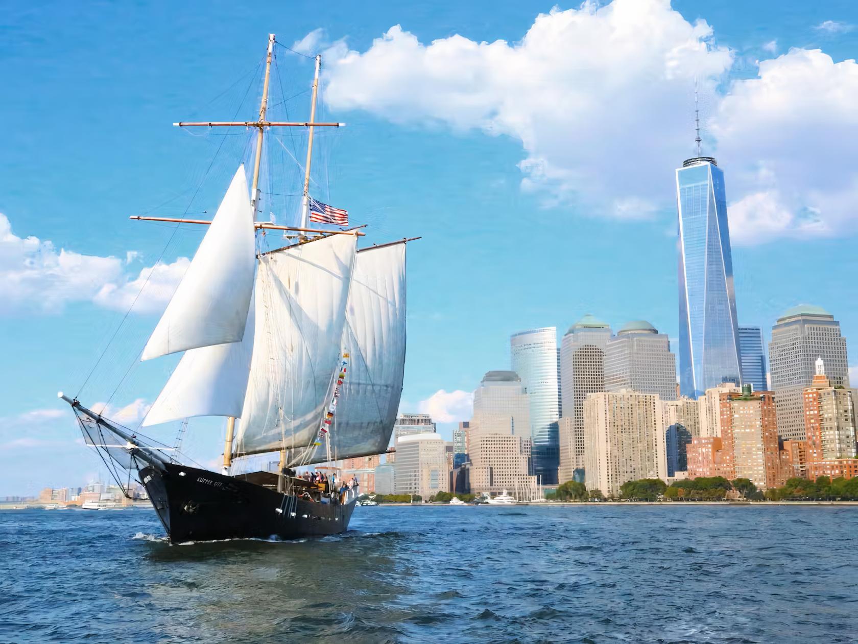 A tall sailing ship with white sails on the water, set against the Manhattan skyline at Clipper City Tall Ship.