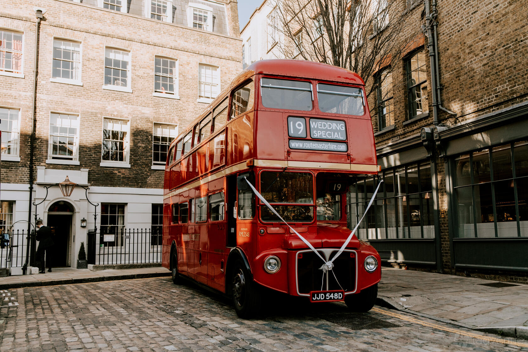 A historic hotel courtyard with cobblestone pavement and a classic red double-decker bus at The Zetter Clerkenwell.