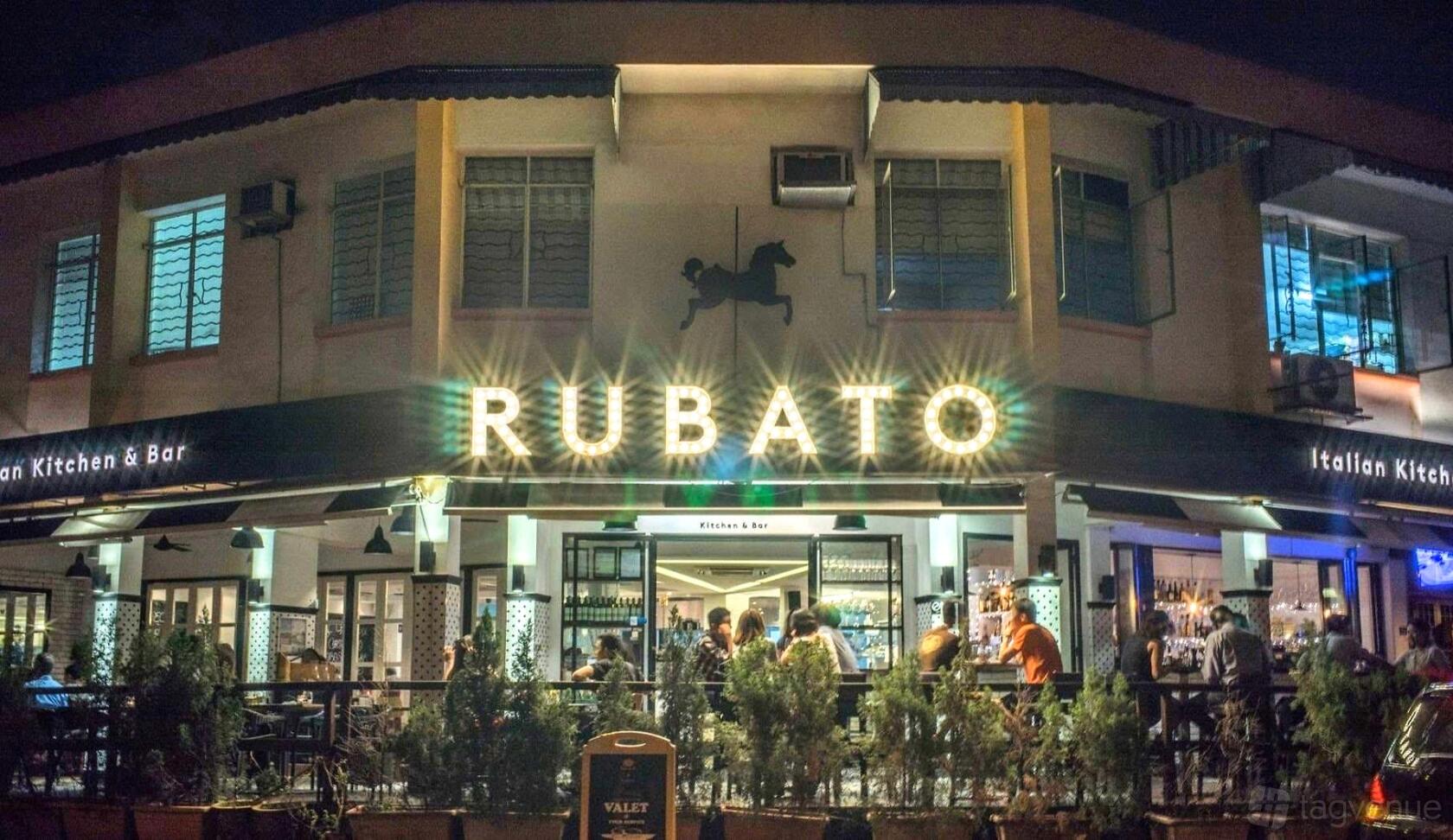A restaurant exterior with illuminated signage, large windows, and outdoor seating at R Italian Kitchen & Smokehouse.
