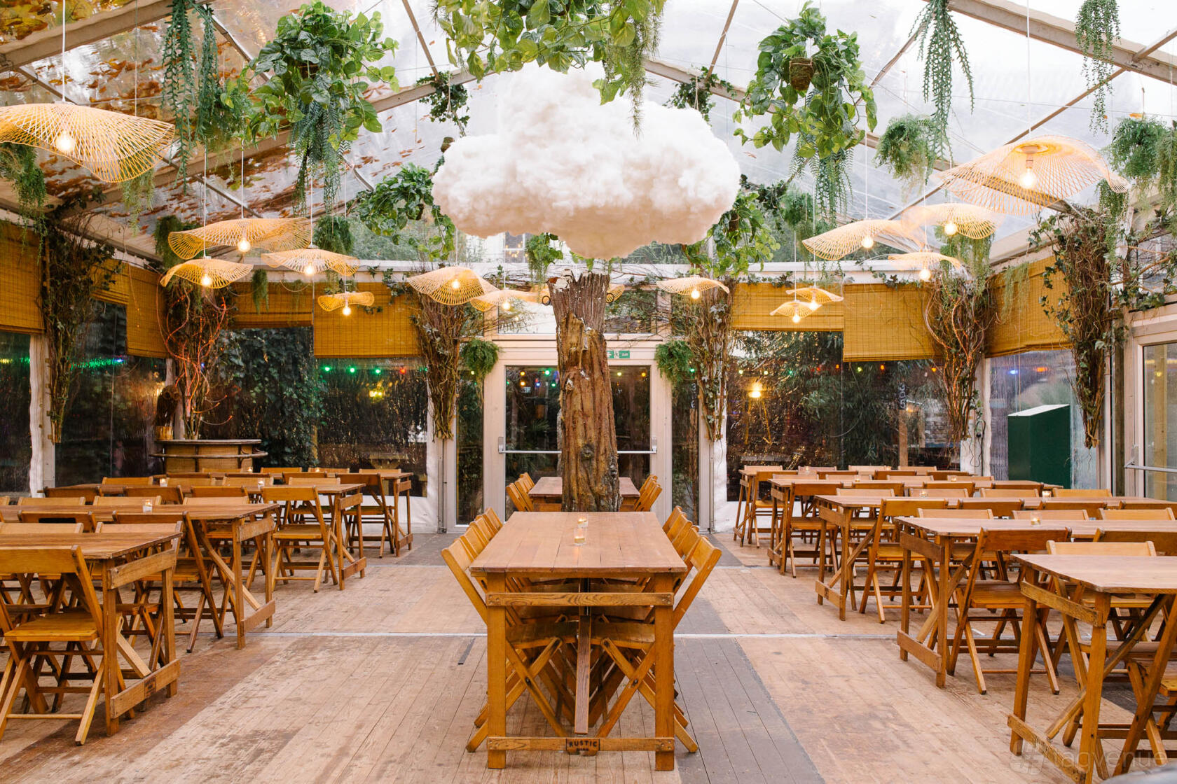 An event space in a pub with wooden tables, hanging greenery, and a large artificial cloud at People's Park Tavern.
