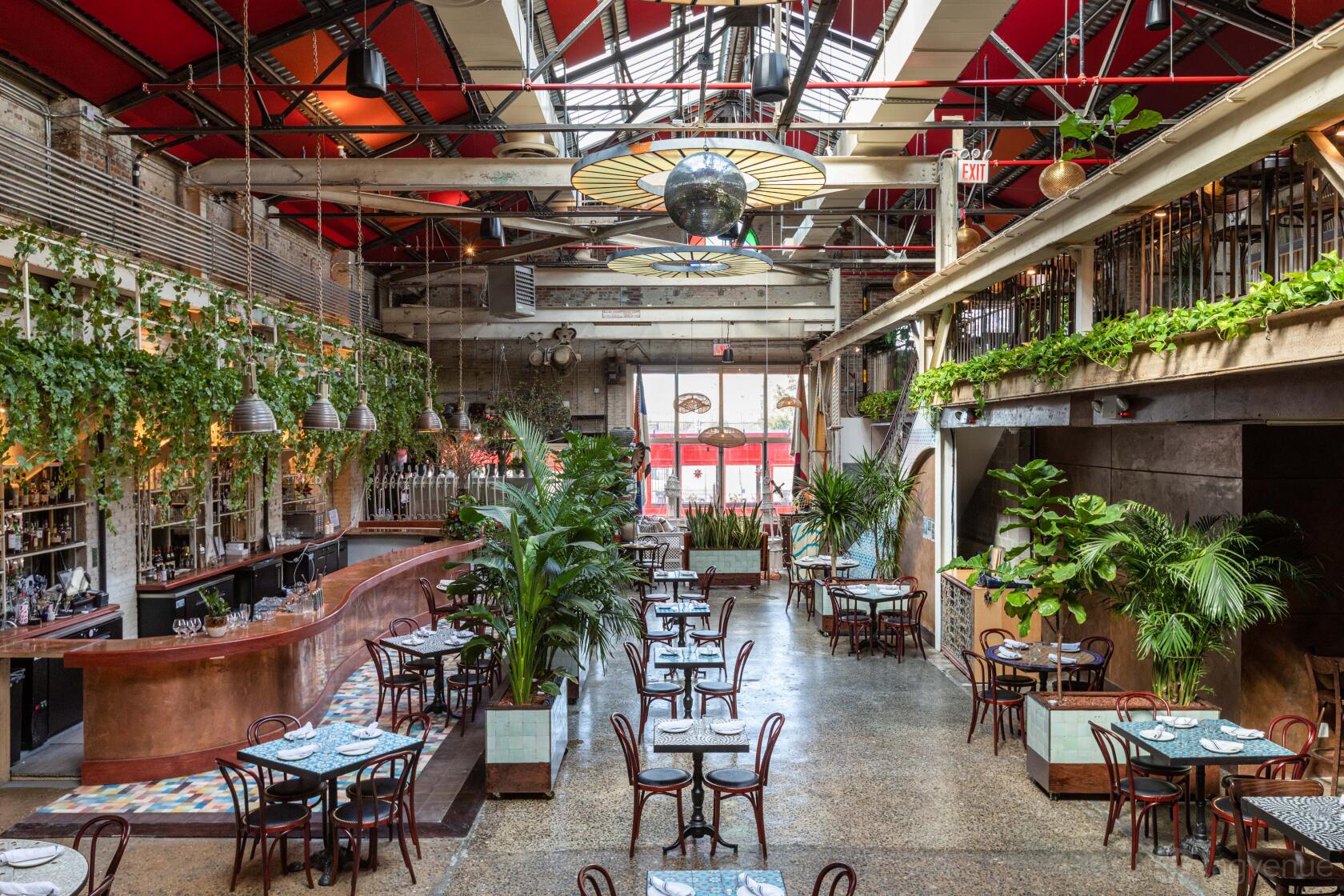 A restaurant with hanging greenery, skylights, and a curved copper bar at Casa FM.