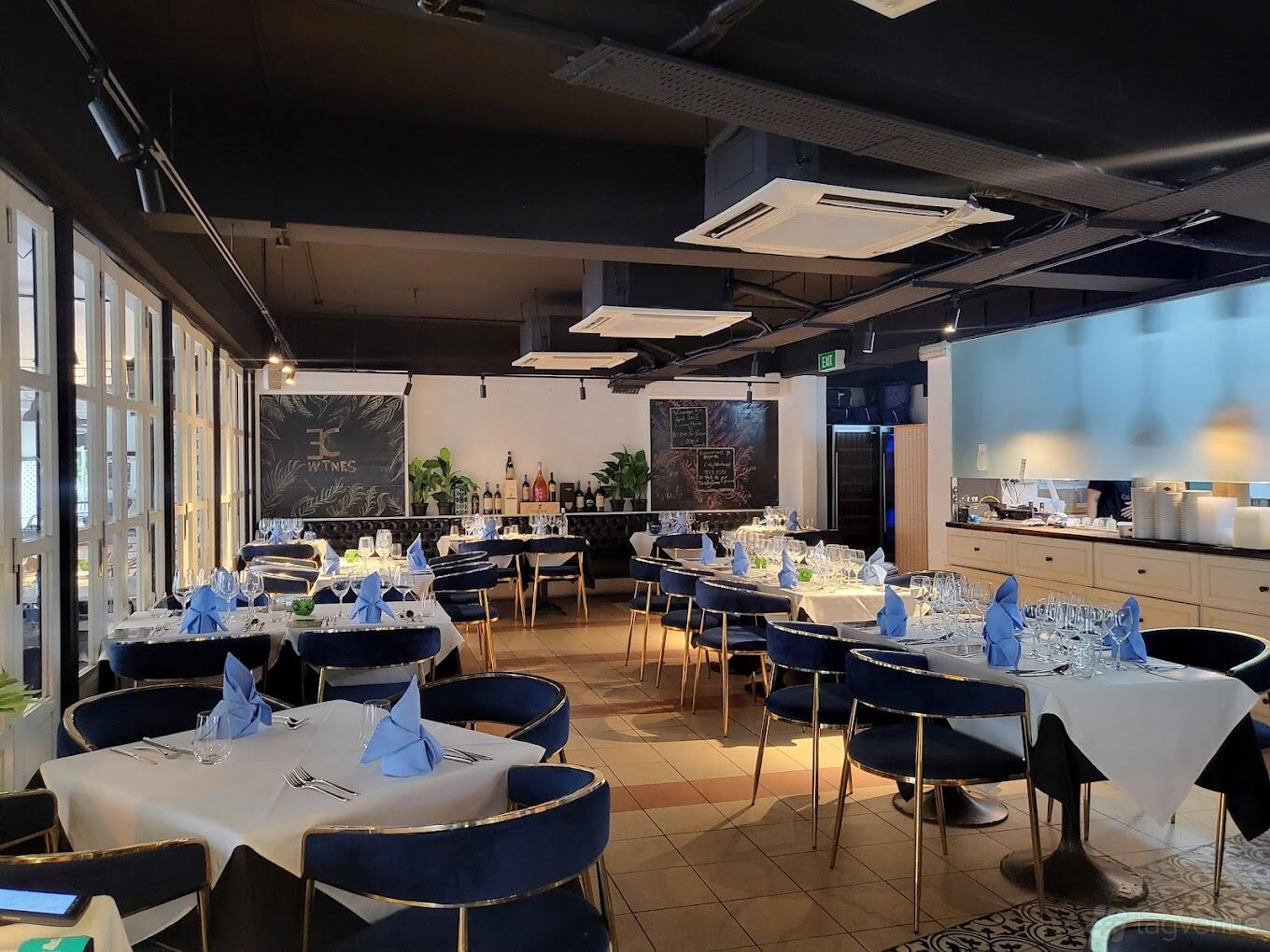 An event space in a restaurant with navy velvet chairs, tables set with blue napkins, and chalkboard menus at R Italian Kitchen & Smokehouse.