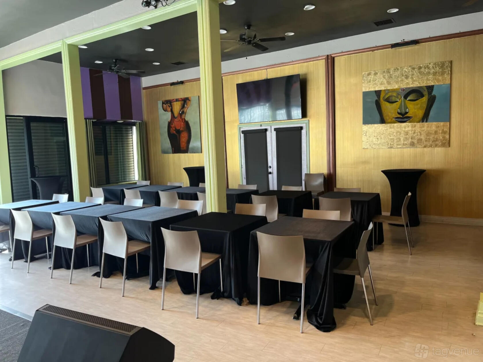 An event venue with black table linens, modern chairs, and colorful wall art at The Nile Spot.