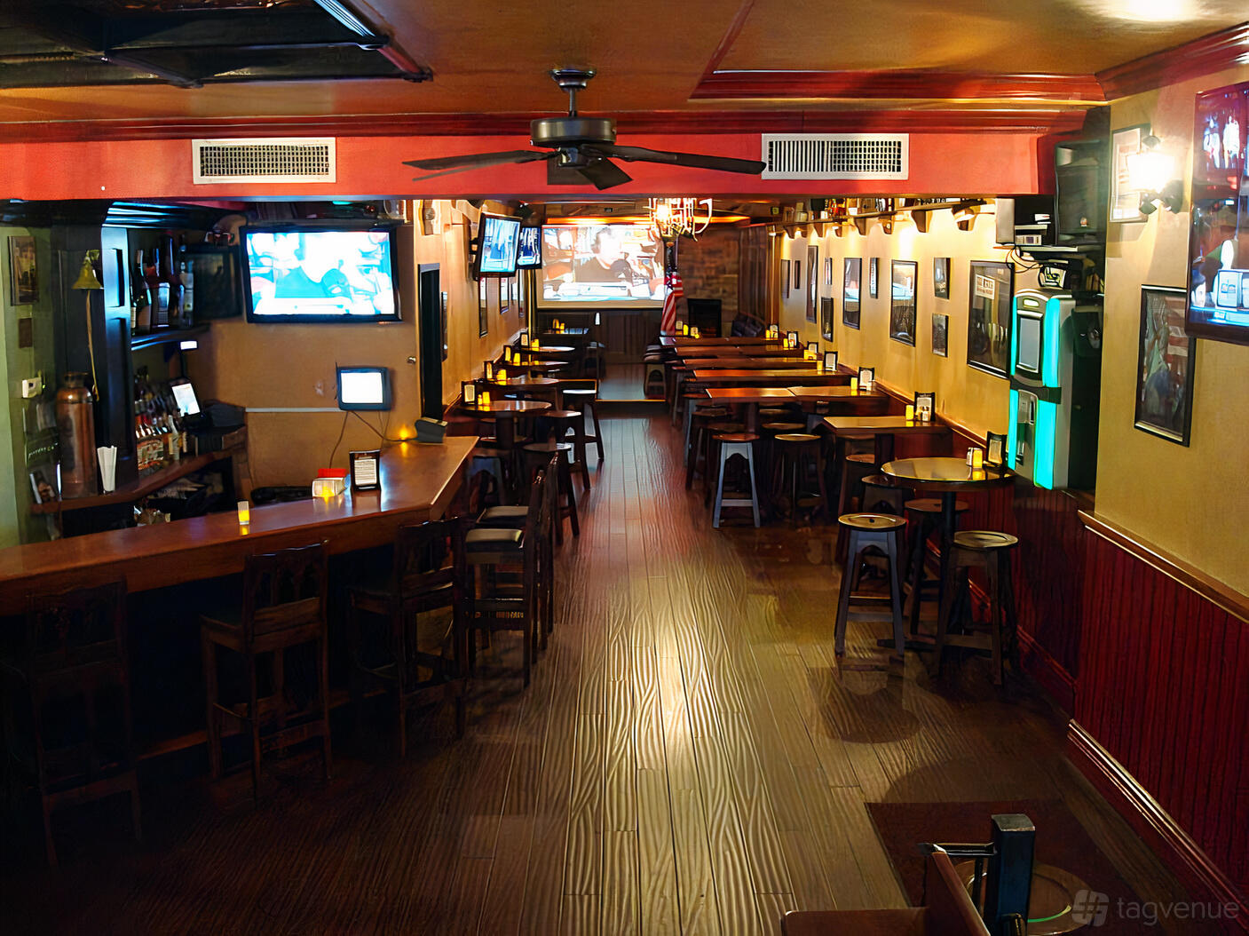 A bar with wooden floors, high-top tables, wall-mounted TVs, and candlelit seating at Slattery's Mid Town Pub.