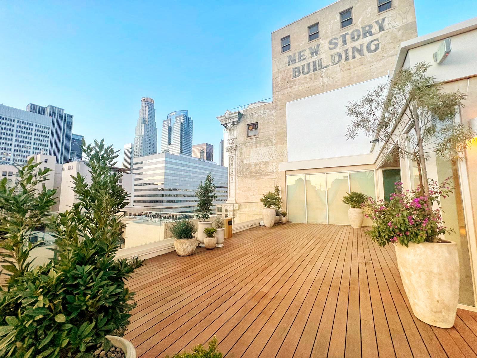 An apartment rooftop with wood decking, potted plants, and city skyline views at Savanna Rooftop.