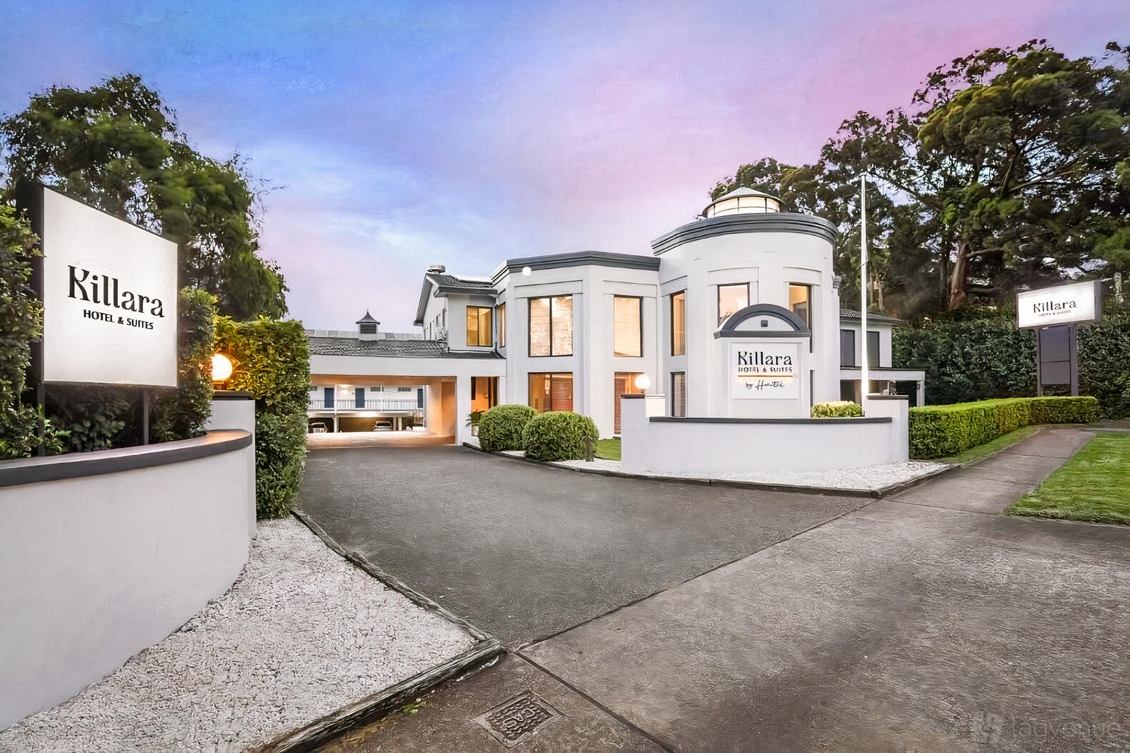 A hotel with a white exterior, large windows, and prominent signage at the entrance at Killara Hotel & Suites.