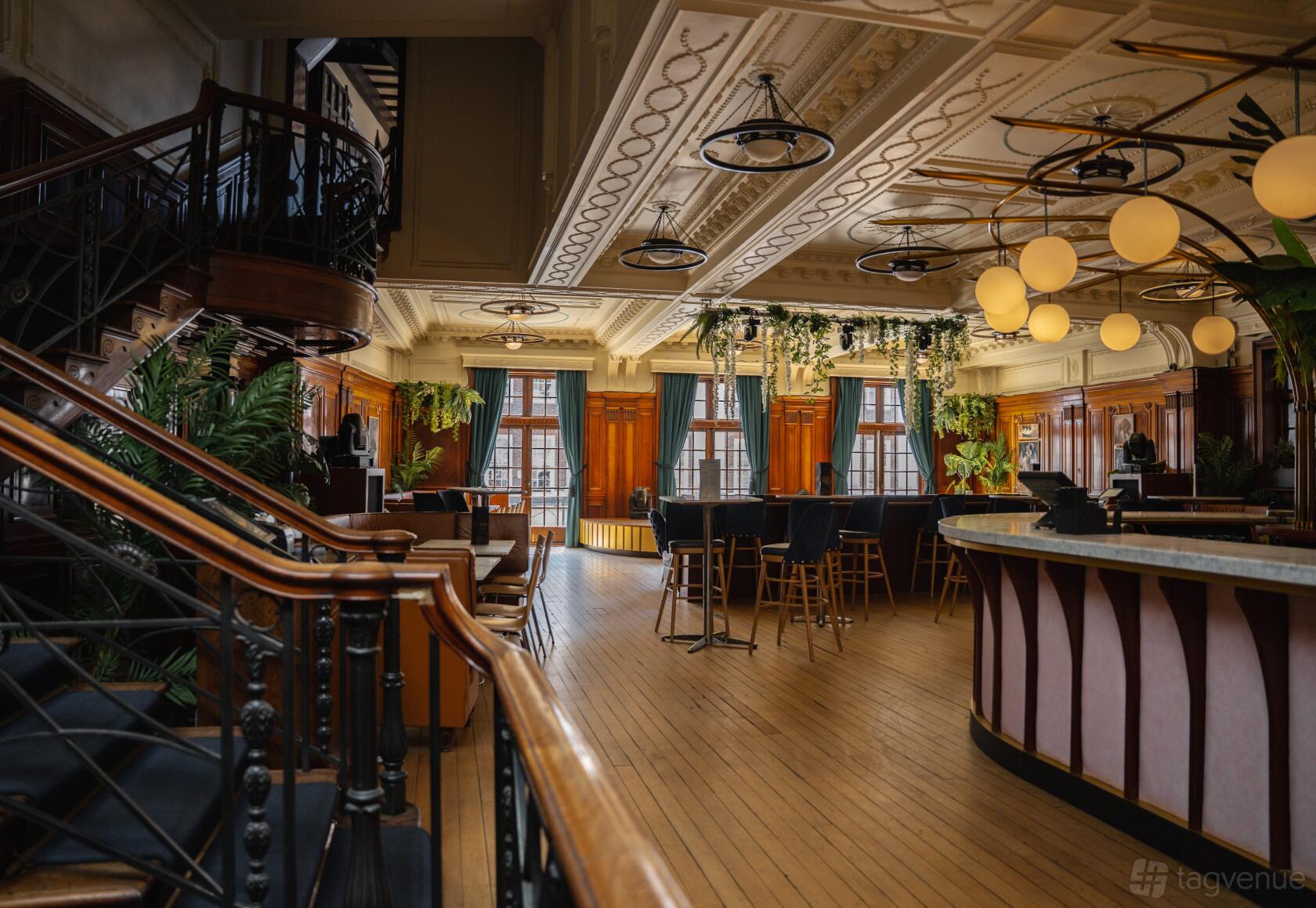 An event space in a restaurant with tall windows, globe pendant lights, and a curved bar at Impossible Wonderbar & Tea Room York.