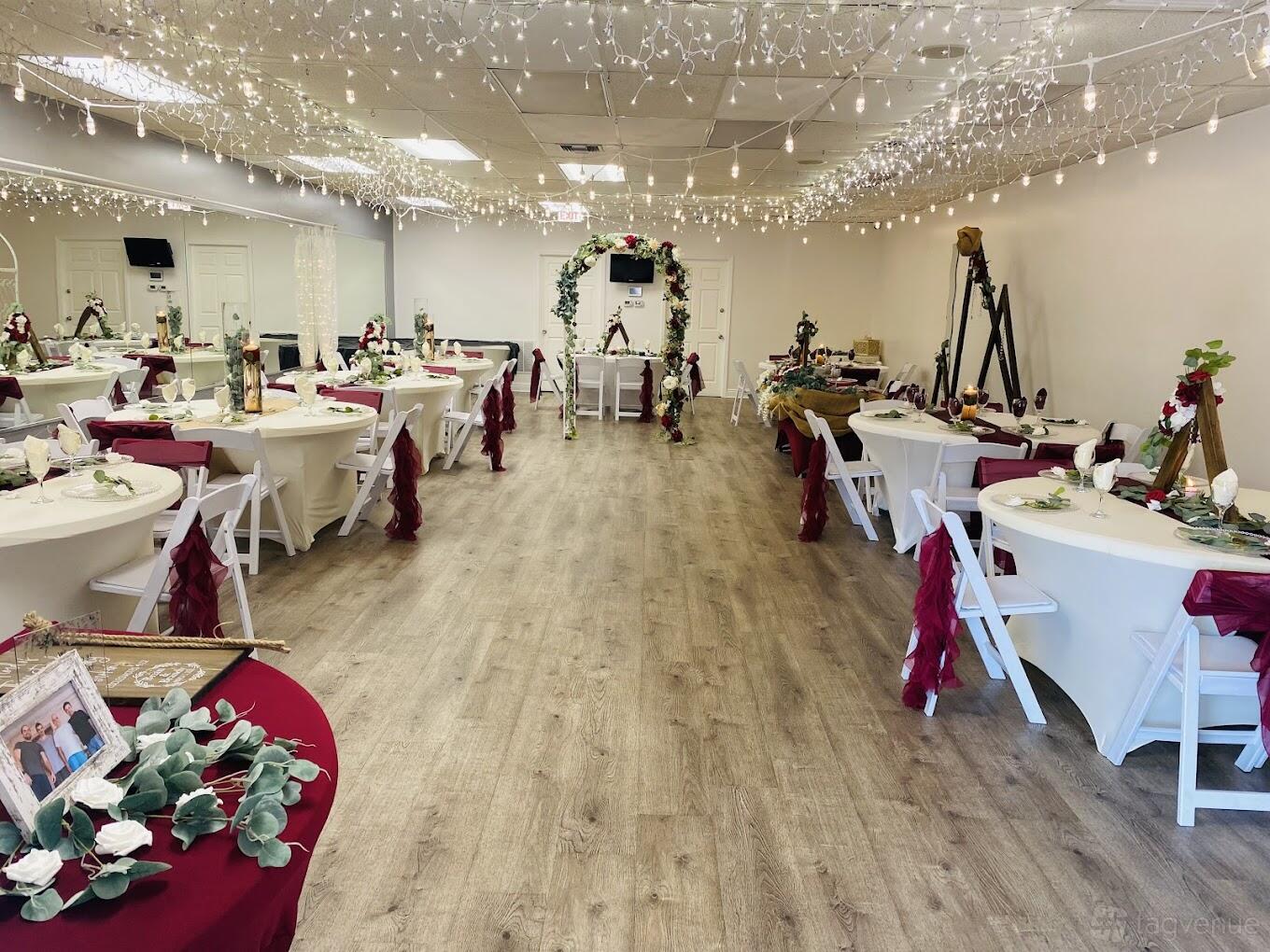 An event venue with round tables draped in red sashes, wooden flooring, and string lights at Celebrations Venue.