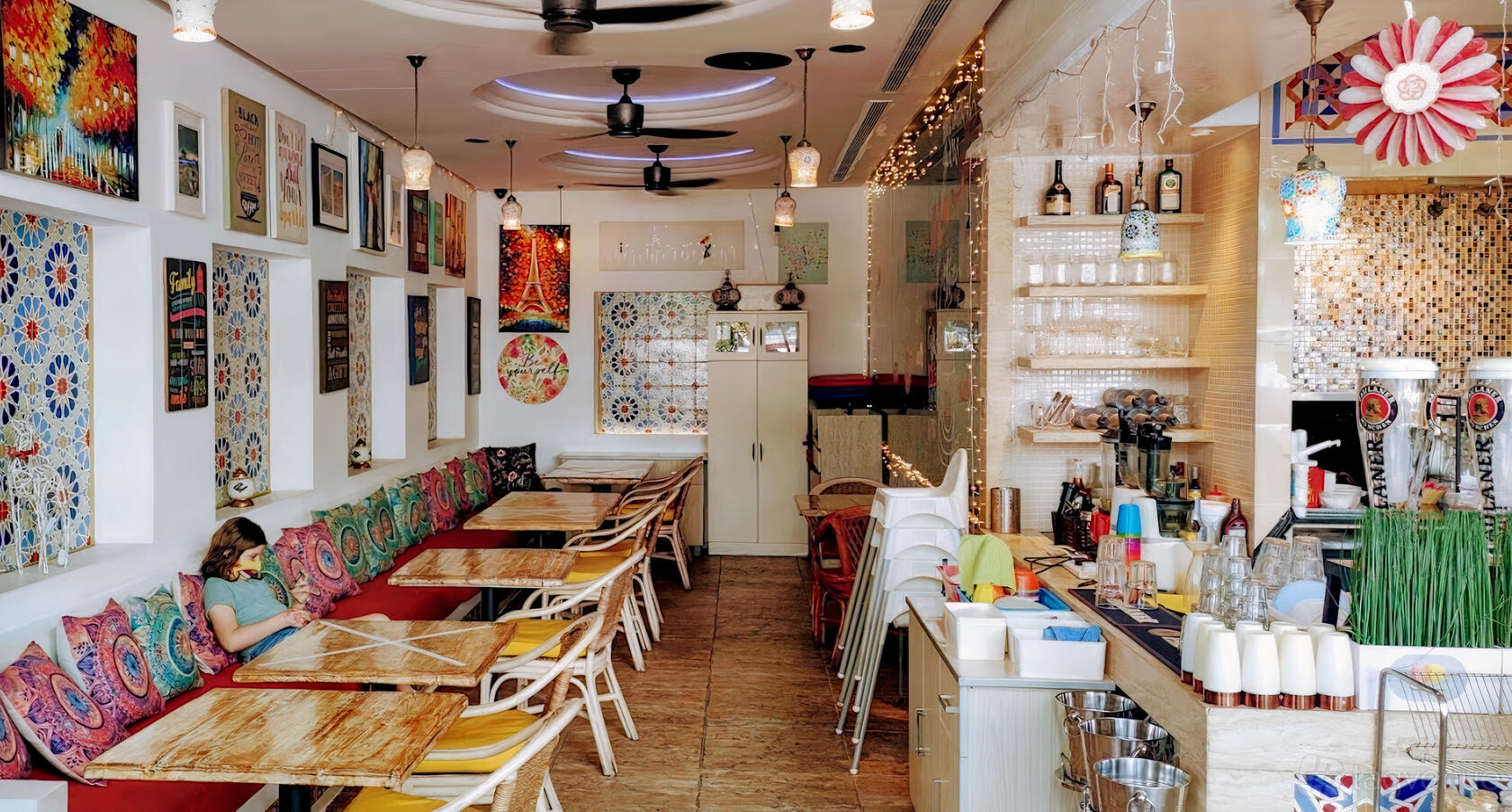 A restaurant with colorful wall art, wooden tables, and patterned bench seating at Miska Cafe.