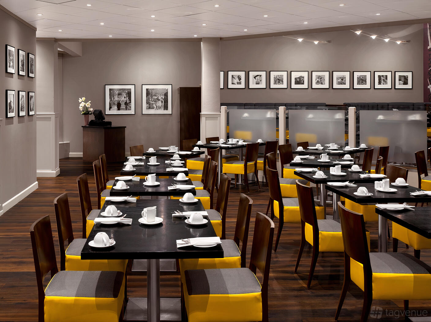 A hotel restaurant with dark wood tables, yellow cushioned chairs, and framed black-and-white photos at Radisson Blu Hotel, Edinburgh City.
