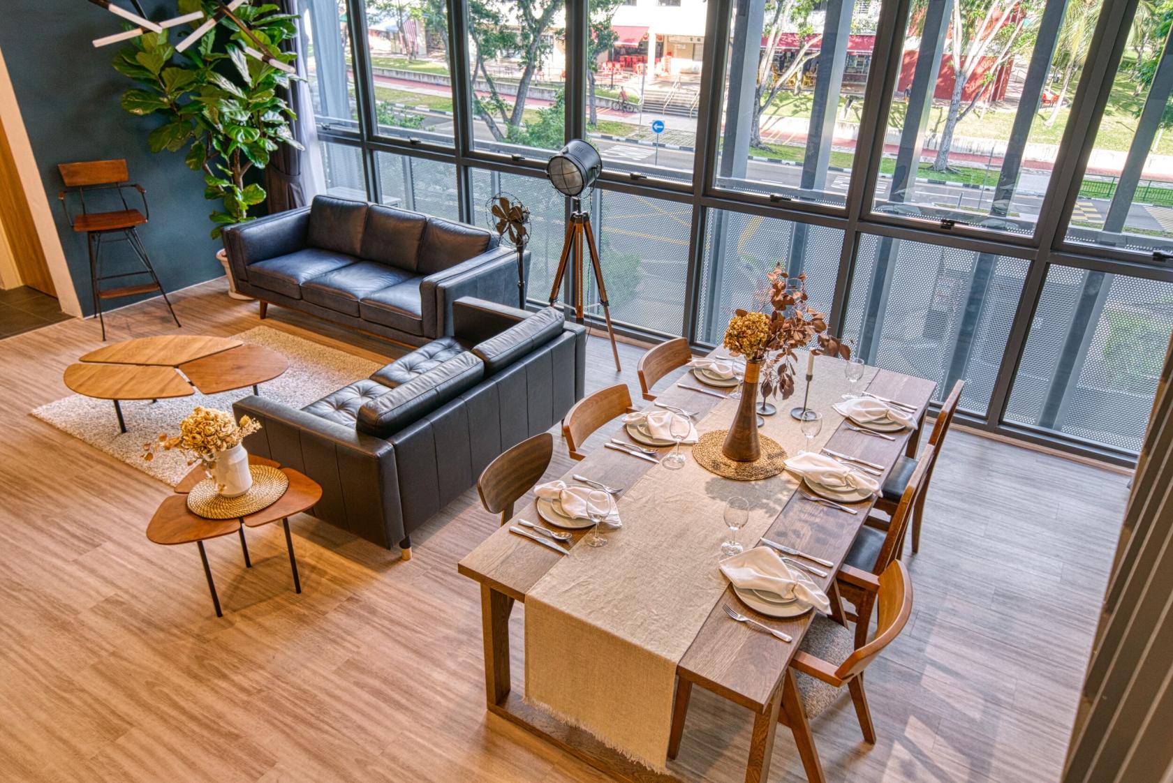 An event space with floor-to-ceiling windows, a dining table set for six, and a lounge area with sofas at Monti Studios.