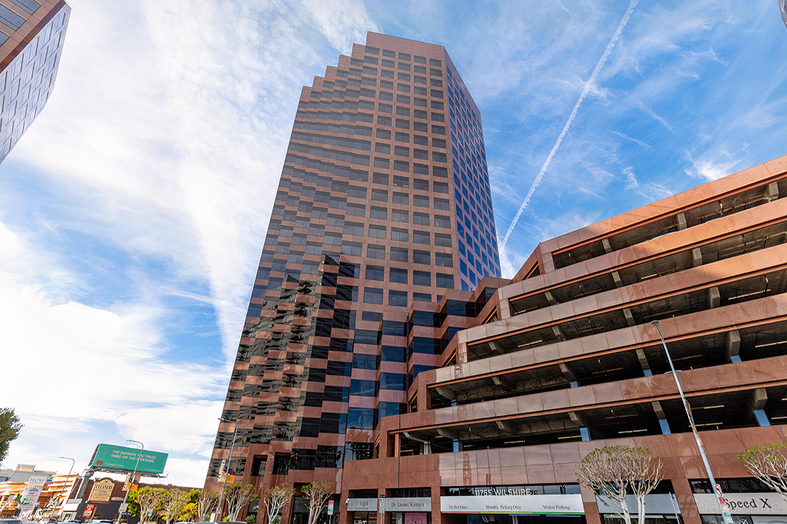 An office building with reflective glass windows and tiered parking at Premier Workspaces - Brentwood.