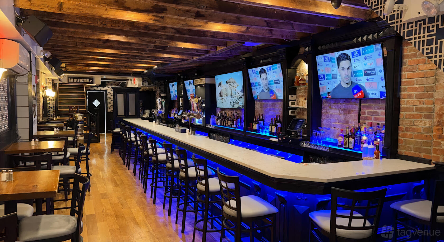 An event space in a bar with a long marble counter, bar stools, exposed wood ceiling, and multiple TVs at McCarthy's Pub.