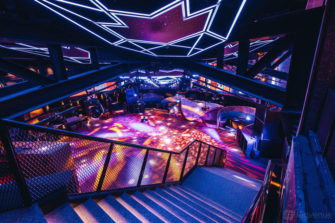 A nightclub with colorful LED ceiling lights, open dance floor, and industrial railings at Zouk.