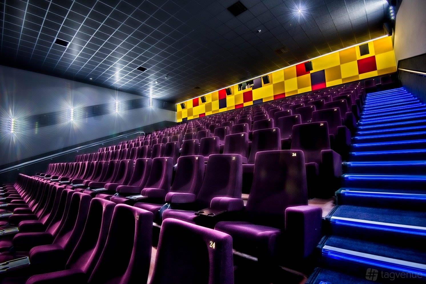 An auditorium with tiered purple seats, illuminated aisle lighting, and a yellow geometric accent wall at The Light Cinema - Walsall.