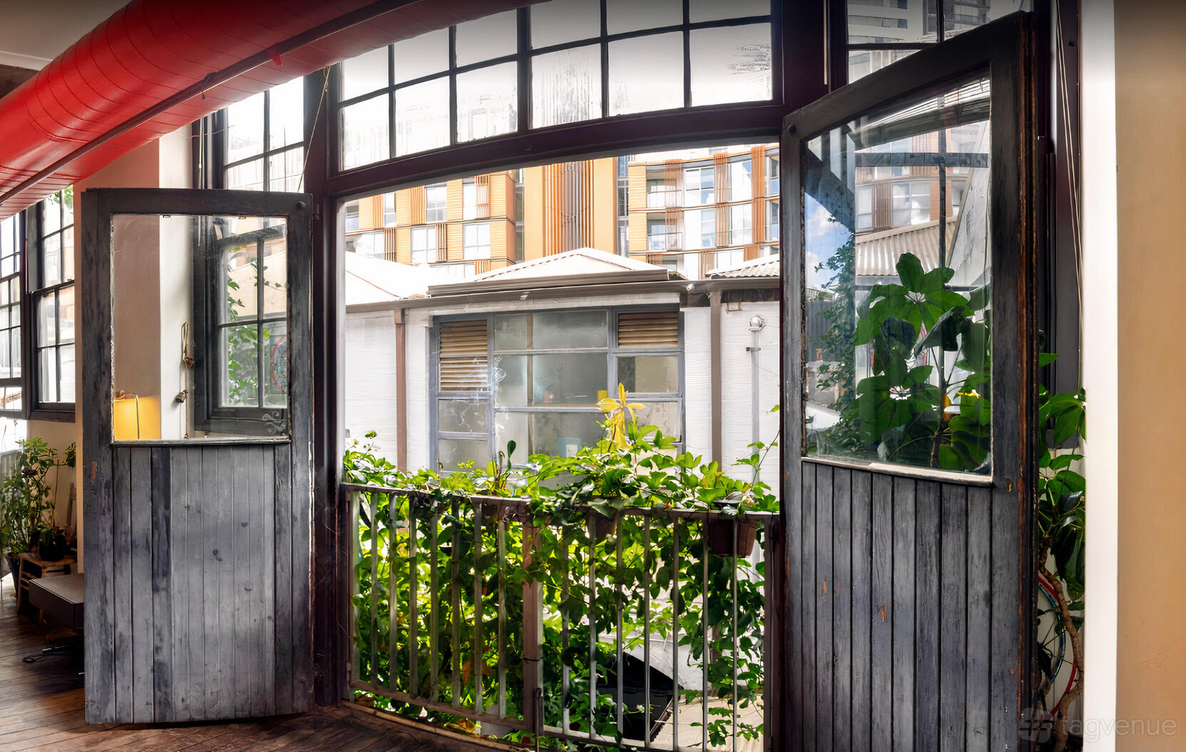 A warehouse with open French doors, balcony railing with greenery, and large arched windows at San Telmo Studio.