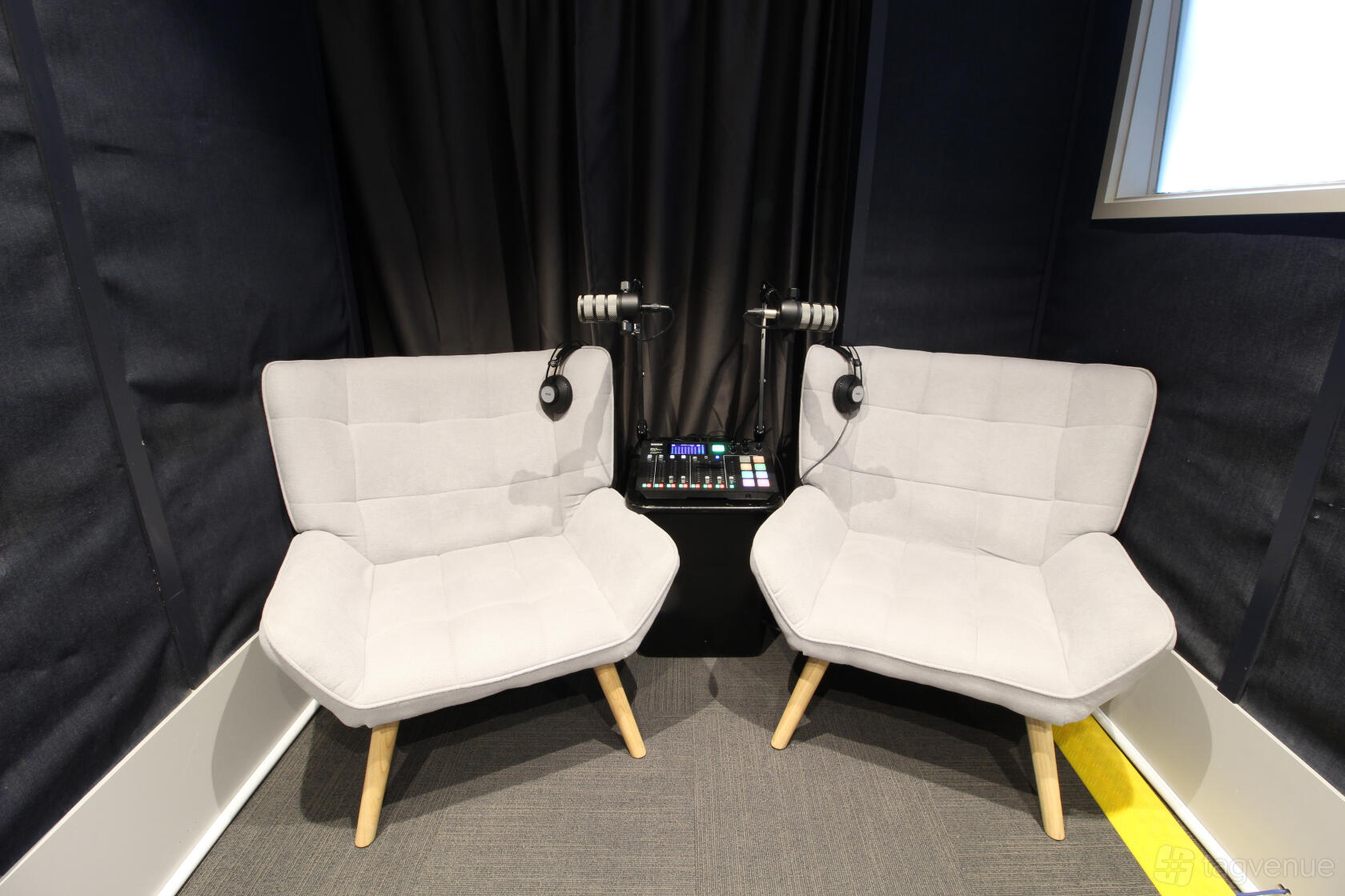 A recording studio with soundproofed walls, two cushioned chairs, and a mixing console at Image On Line.