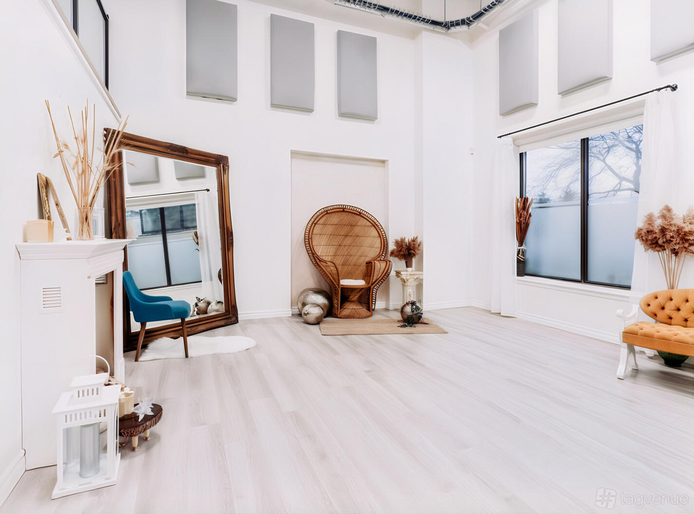 An event venue with high ceilings, large windows, a peacock chair, and decorative mirrors at Velvet Season Studios.